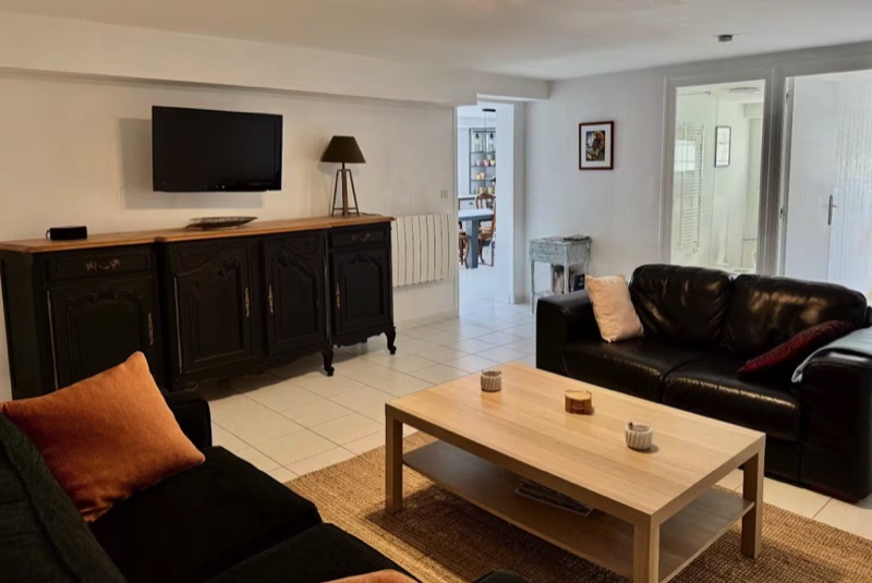 Garden gîte living room with leather sofas and antique sideboard