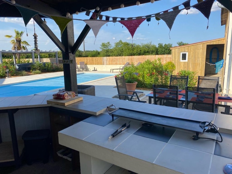 Poolside pergola and outdoor kitchen with plancha grill overlooking the pool and oleander borders
